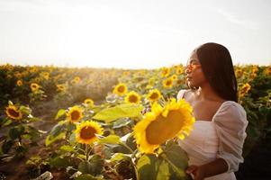 una mujer negra muy joven usa una pose de vestido de verano en un campo de girasoles. foto