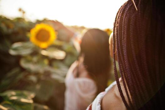 dos jóvenes amigas negras usan pose de vestido de verano en un campo de girasoles. foto