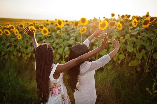 dos jóvenes amigas negras usan pose de vestido de verano en un campo de girasoles. foto