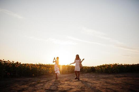 dos jóvenes amigas negras usan pose de vestido de verano en un campo de girasoles. foto