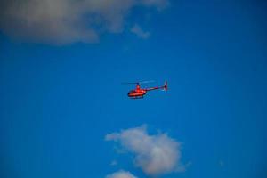 Private pleasure red helicopter flies in the sky on a summer sunny day. L photo