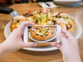 mujer tomando fotos de pizza con teléfono inteligente móvil