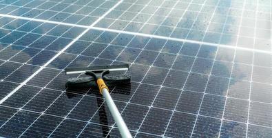 Cleaning solar panel with microfiber mop on wet roof. Solar panel or photovoltaic module maintenance service. Sustainable resource. Solar power. Green energy. Sustainable development technology. photo