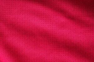 camiseta de fútbol de ropa deportiva de tela roja con fondo de textura de malla de aire foto