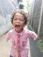 Photo of an expressive boy with curly curls in a red shirt