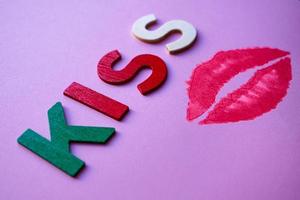 labios y palabra de beso con letras de madera en el fondo rosa foto