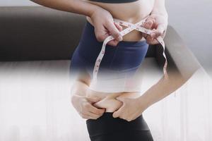 Beautiful fat woman with tape measure She uses her hand to squeeze the excess fat that is isolated on a white background. She wants to lose weight, the concept of surgery and break down fat under the photo