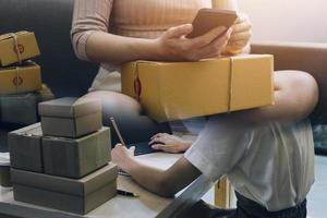 Startup SME small business entrepreneur of freelance Asian woman using a laptop with box Cheerful success Asian woman her hand lifts up online marketing packaging box and delivery SME idea concept photo