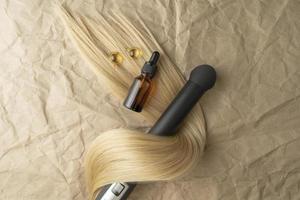 A hair treatment essential oil for smoothing hair lying on a strand of blond hair photo