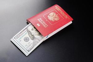 russian international passport with inserted US dollars on black background photo