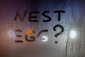 the question nest egg written by finger on night wet glass with blurred lights in background photo