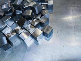 pile of small machined shiny steel cubes on metal surface photo