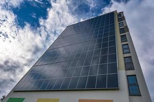 paneles solares en la pared de un edificio de varios pisos sobre fondo de nubes de tormenta. energía solar renovable. un hogar energéticamente eficiente que utiliza la energía de la tierra, el sol, el aire y las aguas residuales foto