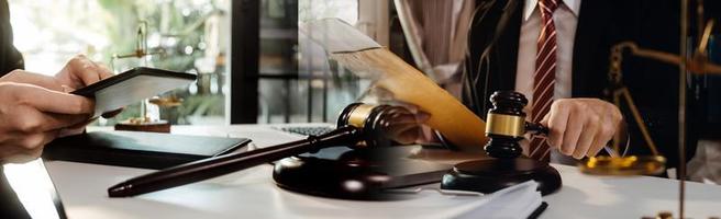 Justice and law concept.Male judge in a courtroom with the gavel, working with, computer and docking keyboard, eyeglasses, on table in morning light photo