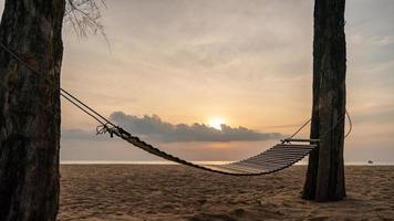 A wooden swing or cradle on the beach with beautiful cloud and sky. photo