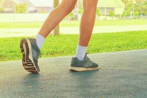 corriendo pies masculino en corredor trotar ejercicio con antiguo Zapatos para salud perder peso concepto en pista caucho cubrir azul público parque. Copiar espacio añadir texto foto