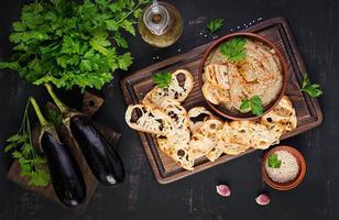 Baba ghanoush vegan hummus from eggplant with seasoning, parsley and toasts. Baba ganoush. Middle Eastern cuisine. Top view, overhead photo
