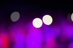 On a black background, large spots of white and purple bokeh. photo