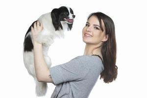 un linda joven mujer es abrazando su Papillon cachorro. amor Entre propietario y perro. niña con perro estudio retrato. foto