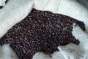 Grain roasted dark arabic coffee. Coffee beans in bag close-up. Background with copy space photo