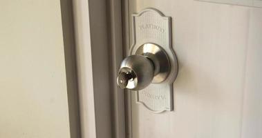 West Jakarta, Indonesia - February 10th, 2023 - Bathroom door knob on closed door with key inside the key hole. Isolated housing photo. photo