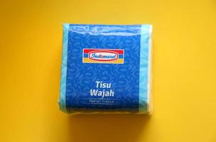 West Jakarta, Indonesia - February 10th, 2023 - Small square Indomaret minimarket shop facial tissue paper. Tisu wajah famous in Indonesia. Health product brand photo isolated on yellow background.