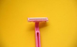 Pink girly razor shaver with holder isolated on yellow background photo