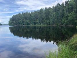 Lake in a forest in Sweden. The trees are reflected in the lake. Cloudy day in summer season. photo