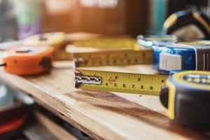 Tape measure with linear-measured markings on wooden background, DIY maker and woodworking concept. selective focus photo