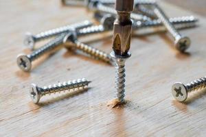 Screwdriver drill a screw into wood plank ,DIY maker and woodworking concept. selective focus photo