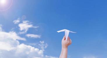 boy hand holding a paper plane The background is a beautiful sky. photo