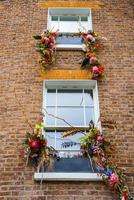 Colorful flowers and leaves decorated on windows of old building in London photo