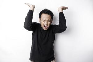 Shocked Asian man wearing black shirt pointing at the copy space on top of him, isolated by white background photo