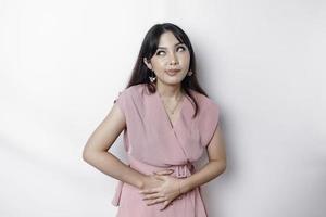 An Asian woman is hungry and touching her belly while looking aside thinking what to eat photo