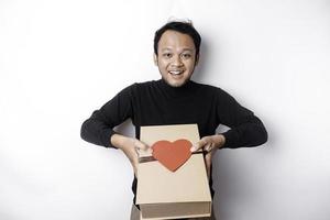 Beautiful young Asian man wearing black shirt holding gift box red heart, Valentine's Day concept. photo