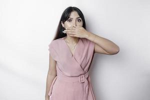 Surprised young Asian woman covering mouth with hands and staring at camera while standing against white background photo