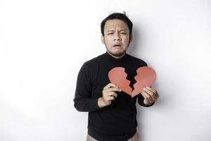 hermosa joven asiático hombre expresado su tristeza mientras participación roto corazón aislado en blanco antecedentes foto