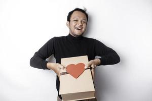 Beautiful young Asian man wearing black shirt holding gift box red heart, Valentine's Day concept. photo