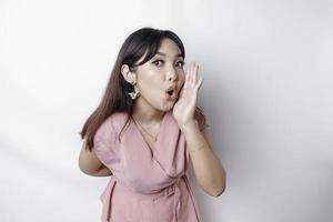 Young beautiful woman wearing a pink blouse shouting and screaming loud with a hand on her mouth. communication concept. photo