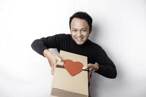hermosa joven asiático hombre vistiendo negro camisa participación regalo caja rojo corazón, San Valentín día concepto. foto