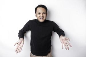 Excited Asian man wearing black shirt pointing at the copy space below him, isolated by white background photo