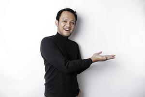 Excited Asian man wearing black shirt pointing at the copy space beside him, isolated by white background photo