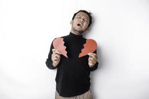 Beautiful young Asian man expressed his sadness while holding broken heart isolated on white background photo