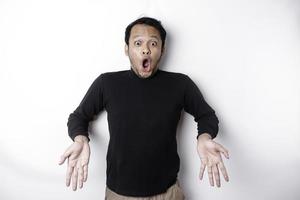 Shocked Asian man wearing black shirt, pointing at the copy space below him, isolated by white background photo