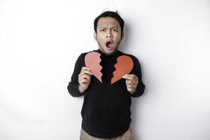 Beautiful young Asian man expressed his sadness while holding broken heart isolated on white background photo