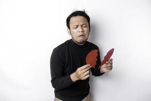 Beautiful young Asian man expressed his sadness while holding broken heart isolated on white background photo