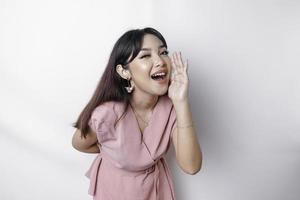 joven hermosa mujer vistiendo un rosado blusa gritos y gritando ruidoso con un mano en su boca. comunicación concepto. foto