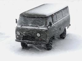 green military SUV in the snow in a blizzard photo