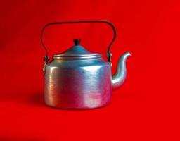 Old soldier's aluminum teapot from the Second World War on a red background. photo