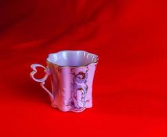 porcelana rosado taza de un raro forma es hecho en el checo república. un taza con un romántico modelo en un rojo antecedentes. foto